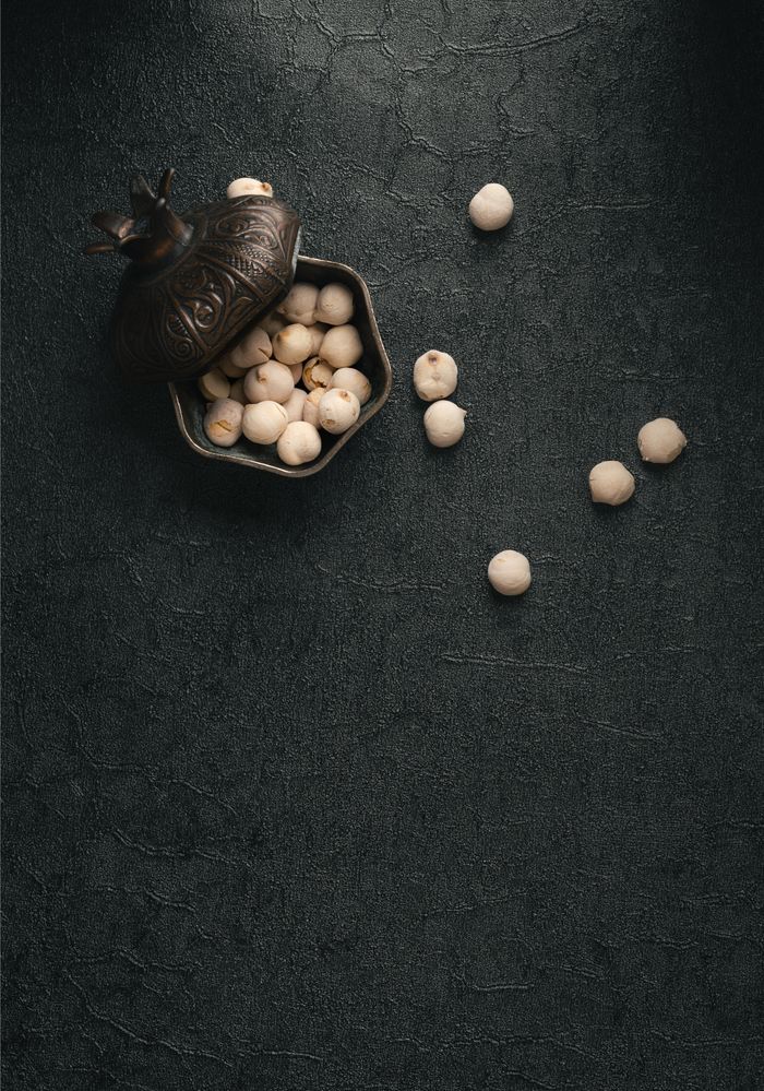 pexels photo 35794691 Artistic still life featuring lotus seeds in an ornate bowl on a textured surface.